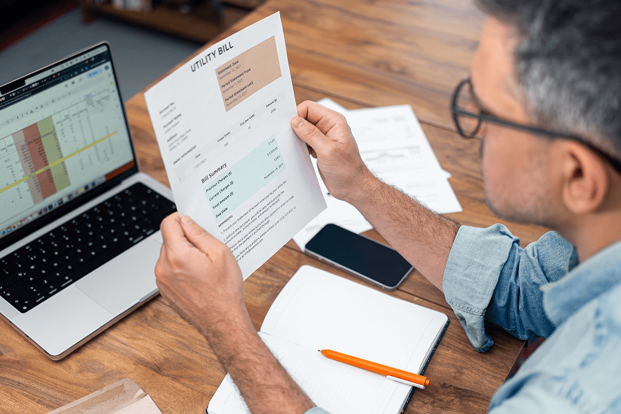 Man reviewing utility bill at desk.