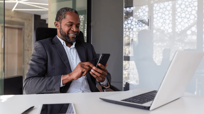 A business man happily typing on his mobile phone