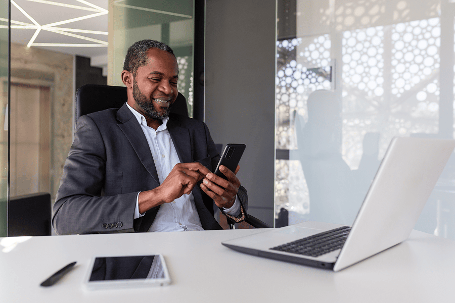 A business man happily typing on his mobile phone