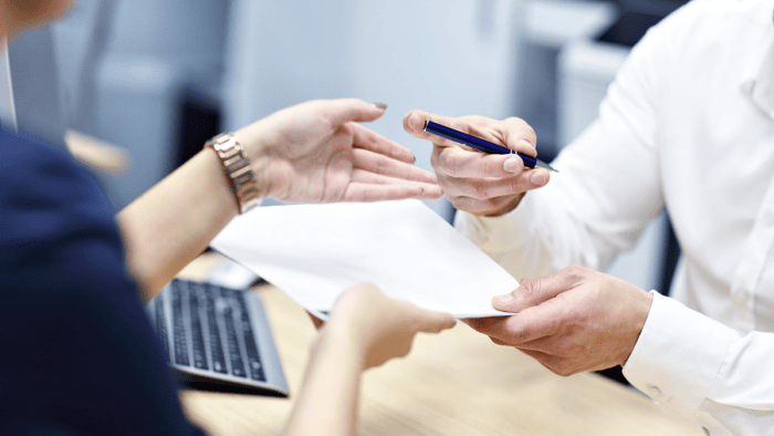 Hands exchanging documents and pen.