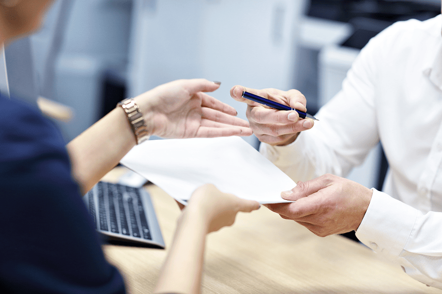 Hands exchanging documents and pen.