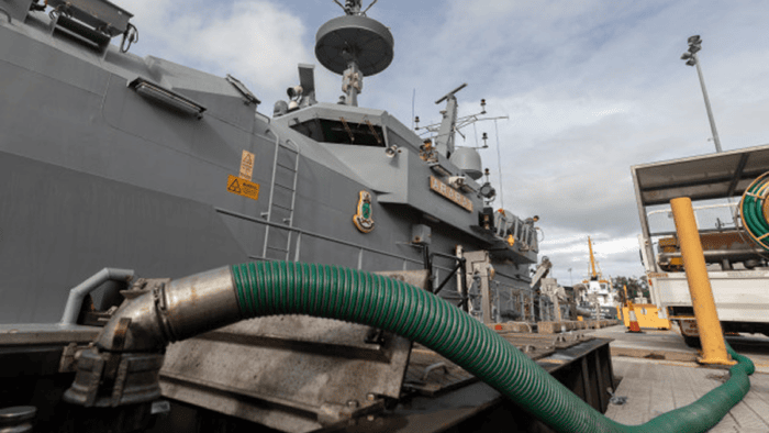 A naval ship undergoing military refueling operations at sea to maintain maritime defense readiness