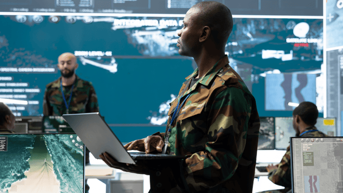 A military specialist holding an open laptop during command operations