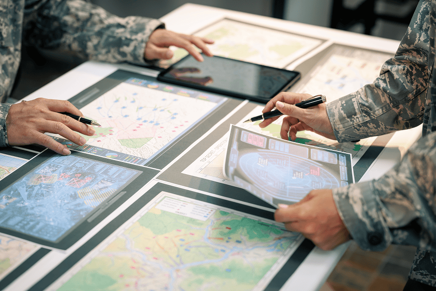A tactical military team wearing camouflage uniforms studies topographic maps