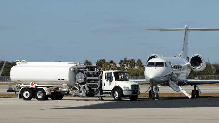 Fuel truck servicing a commercial aircraft on the airport apron.