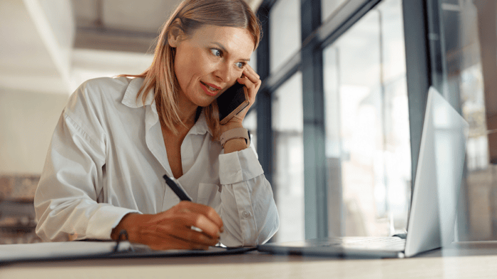 Woman on phone, taking notes diligently.