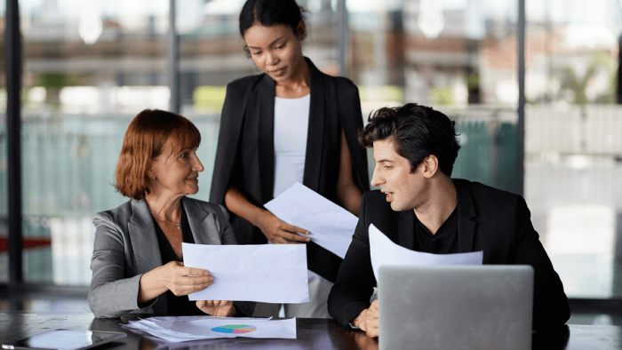 Three colleagues discussing documents together.