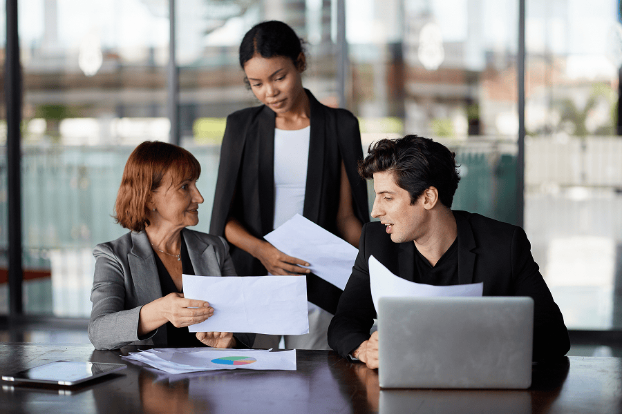 Three colleagues discussing documents together.