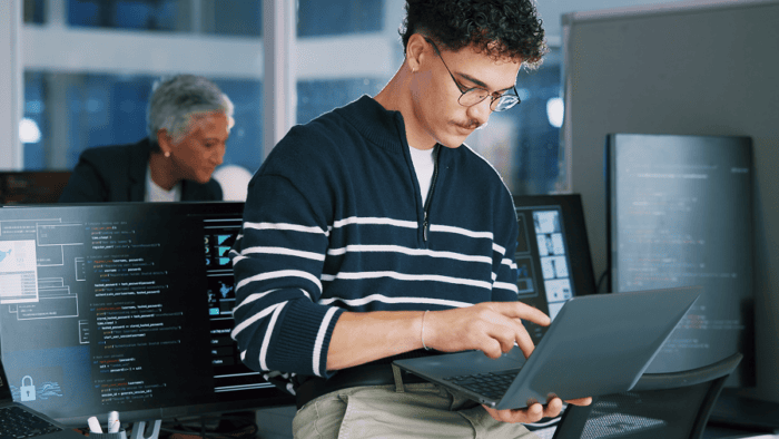 Young man coding in modern office.