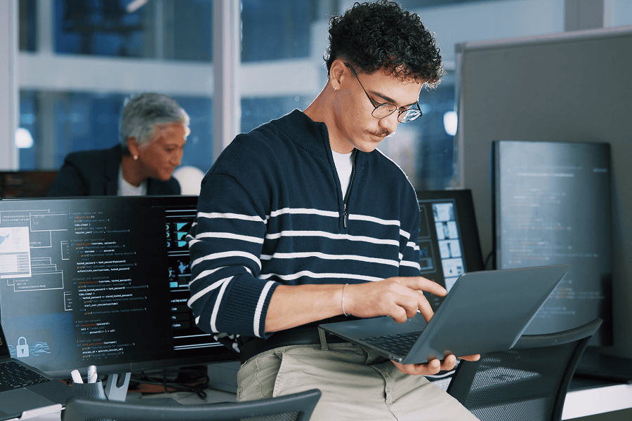 Young man coding in modern office.