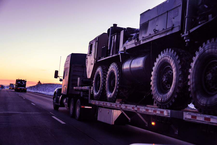 A heavy-duty logistics transport truck carrying a military vehicle