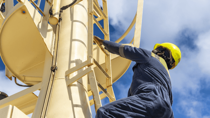 Ship officer ascending a ladder toward the navigation mast platform on a vessel