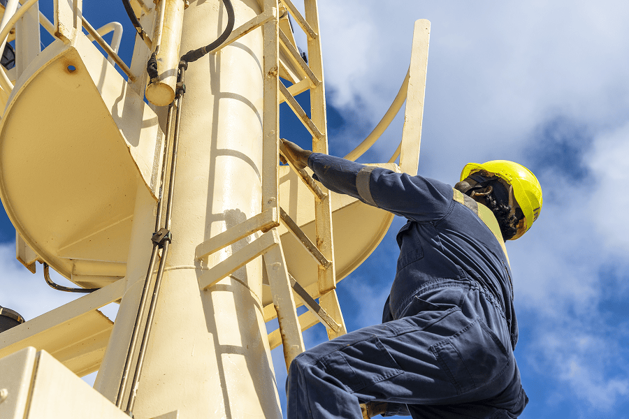 Ship officer ascending a ladder toward the navigation mast platform on a vessel