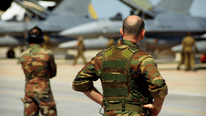 A military soldier standing on an airfield runway monitoring aircraft operations