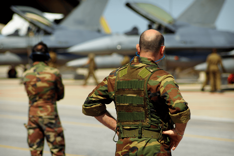 A military soldier standing on an airfield runway monitoring aircraft operations