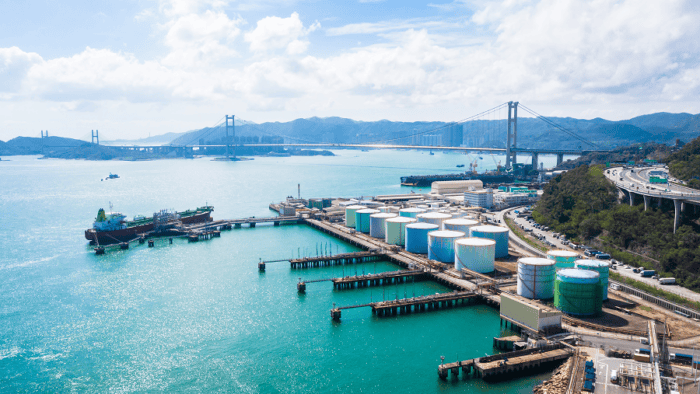A maritime tank ship loading and unloading oil and gasoline at a commercial dock facility