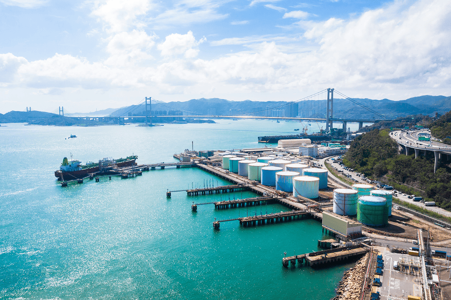 A maritime tank ship loading and unloading oil and gasoline at a commercial dock facility