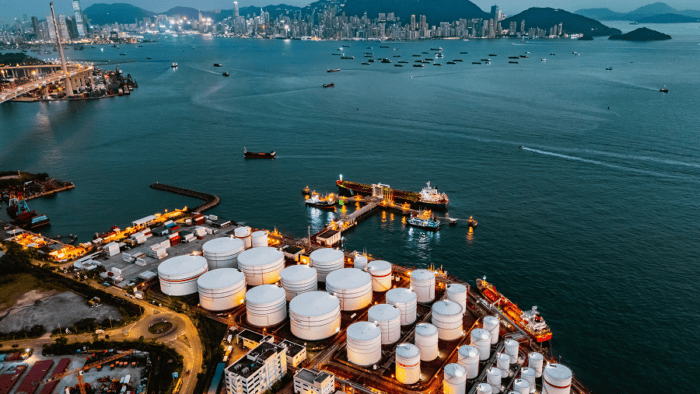 A maritime tank ship loading and unloading oil and gasoline at a commercial dock facility