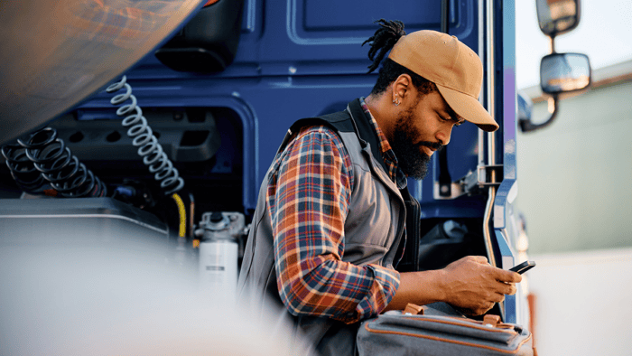 Man leaning on truck while looking at phone