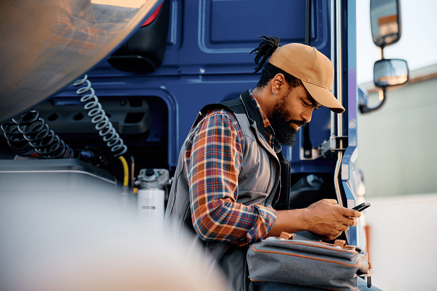 Man leaning on truck while looking at phone