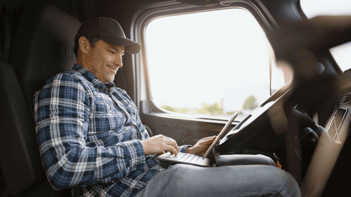 Man sitting in truck while looking at laptop