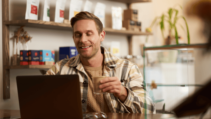 man drinking coffee while looking at laptop