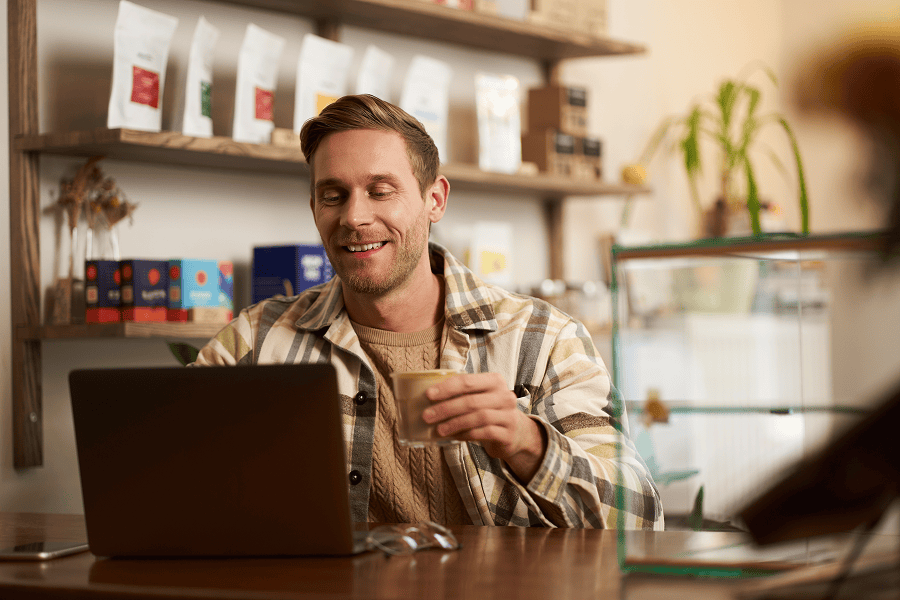 man drinking coffee while looking at laptop